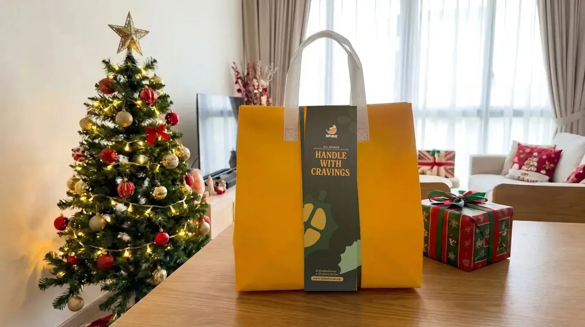 A Spike Durian yellow insulated bag on a table beside a Christmas tree and a wrapped present